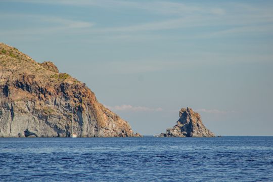A wide view of cliffs and a rock formation offshore