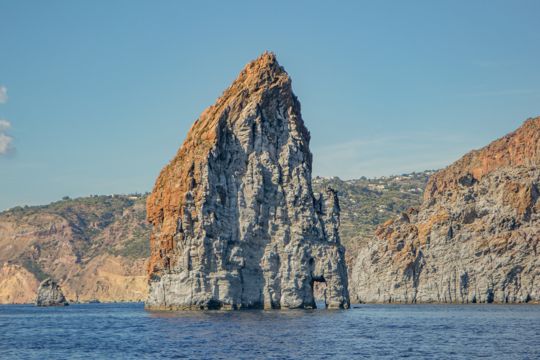 A tall, angular sea stack close to the coastline